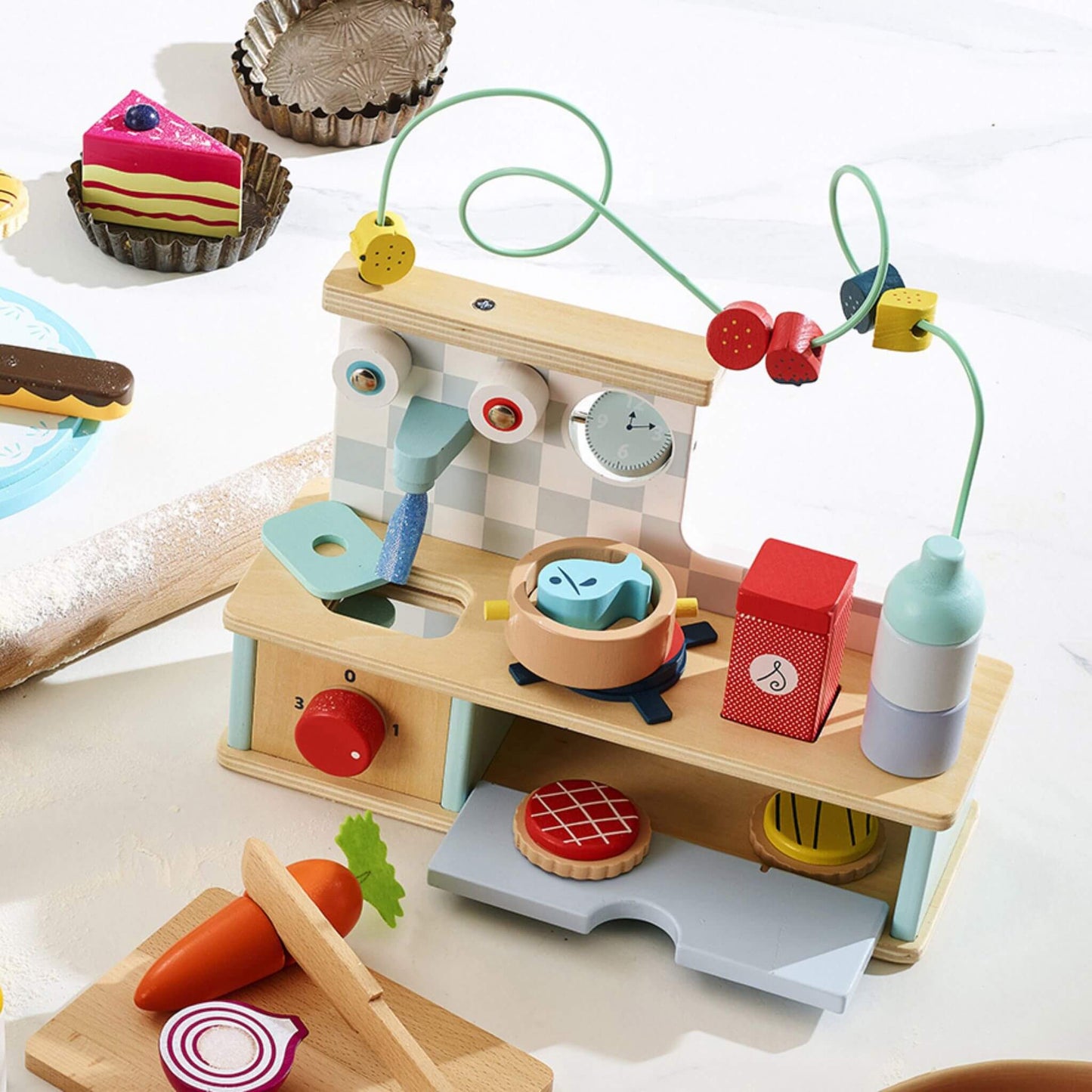 Wooden kitchen playset in baking scene with colourful pastries, fruit bead maze, sink and cooktop for imaginative play.