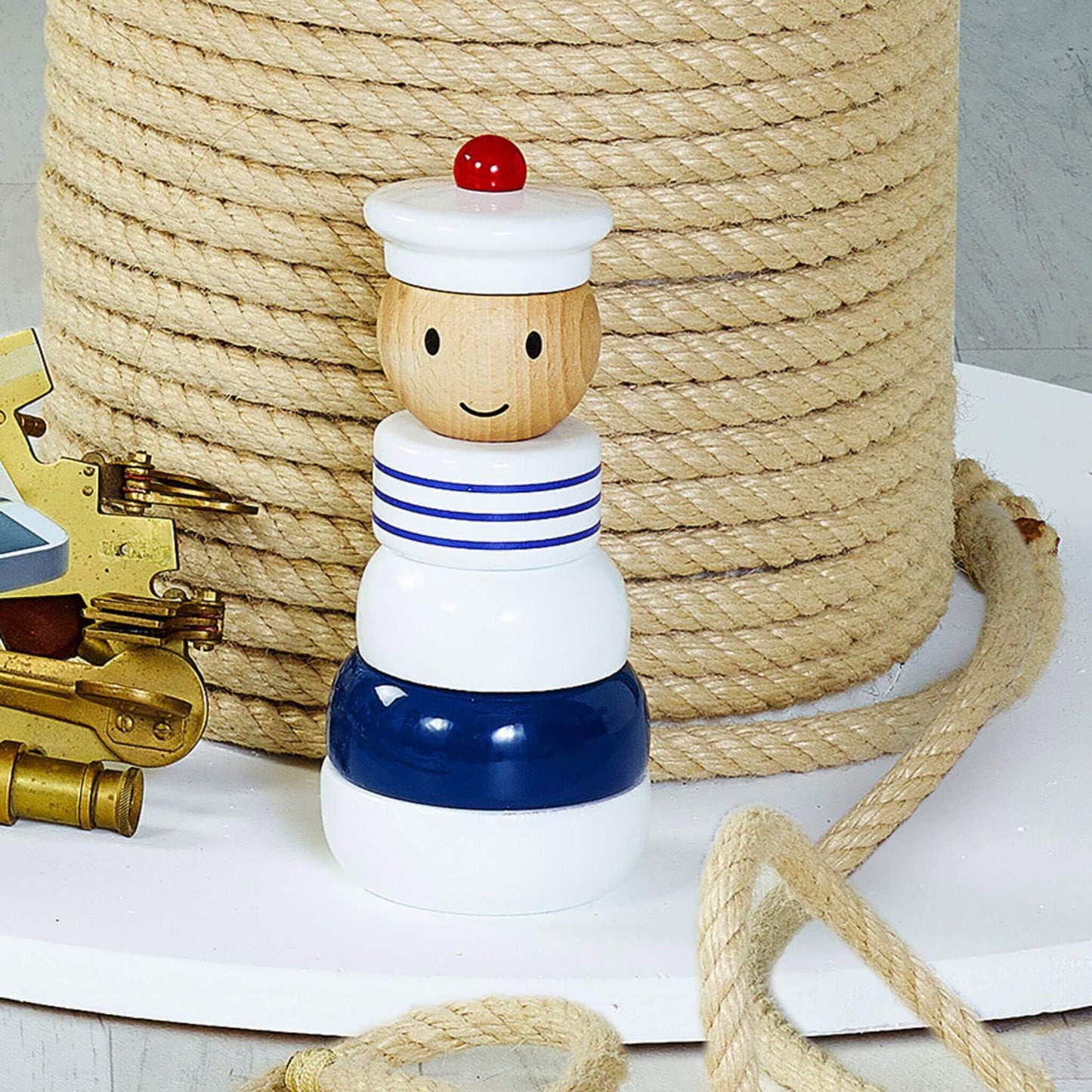Wooden Stacking Toy displayed on a nautical-themed setup with coiled rope and brass accessories, featuring its french sailor design.
