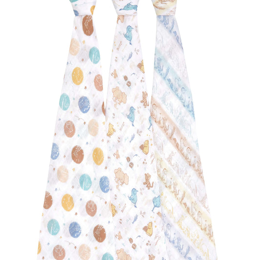 Three aden + anais cotton muslin swaddles hanging to show full Winnie the Pooh and forest-themed prints in soft greens, browns, and blues.