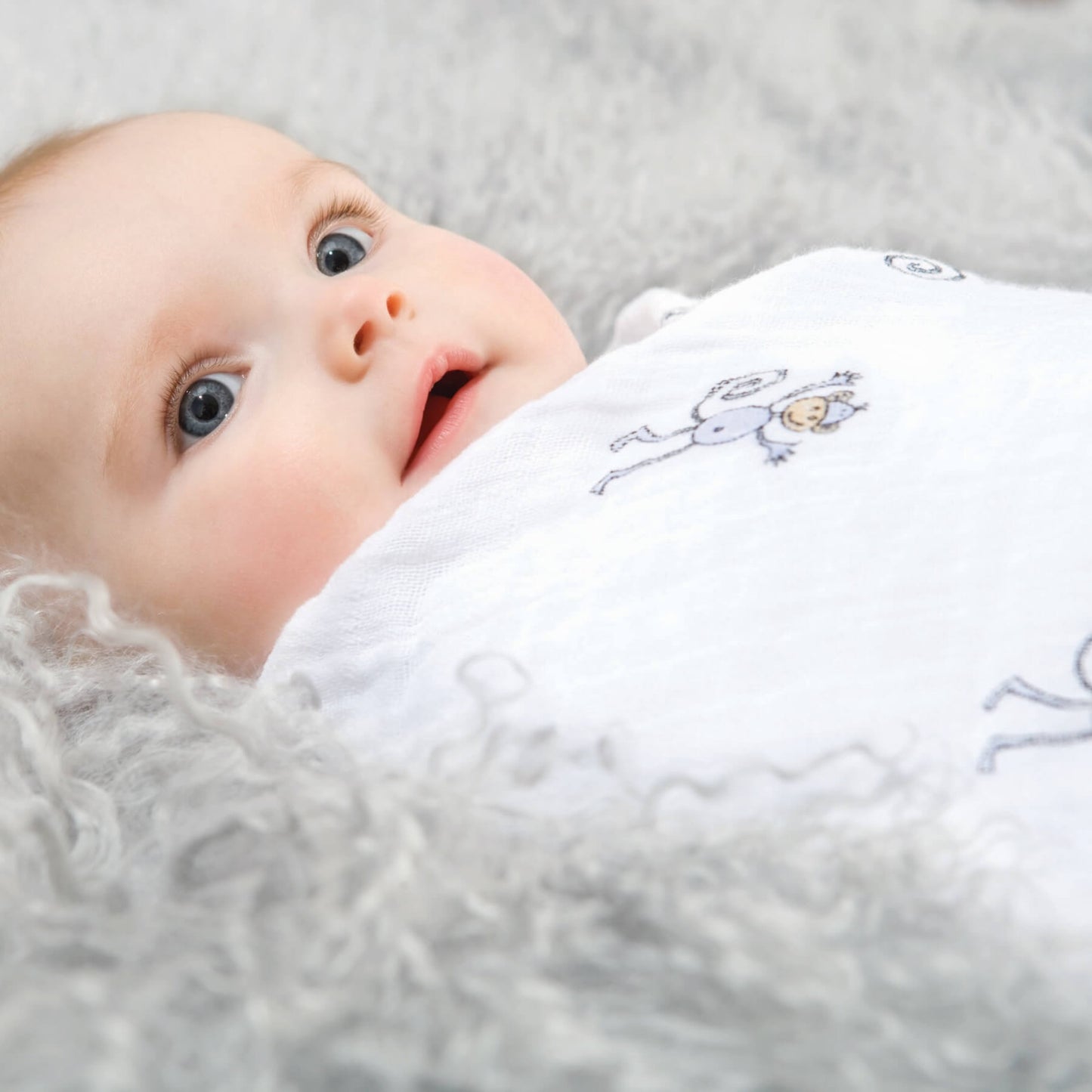 Baby swaddled in aden + anais Jungle Jam monkey print muslin blanket. Gentle, soft fabric ideal for snuggles and naptime comfort.