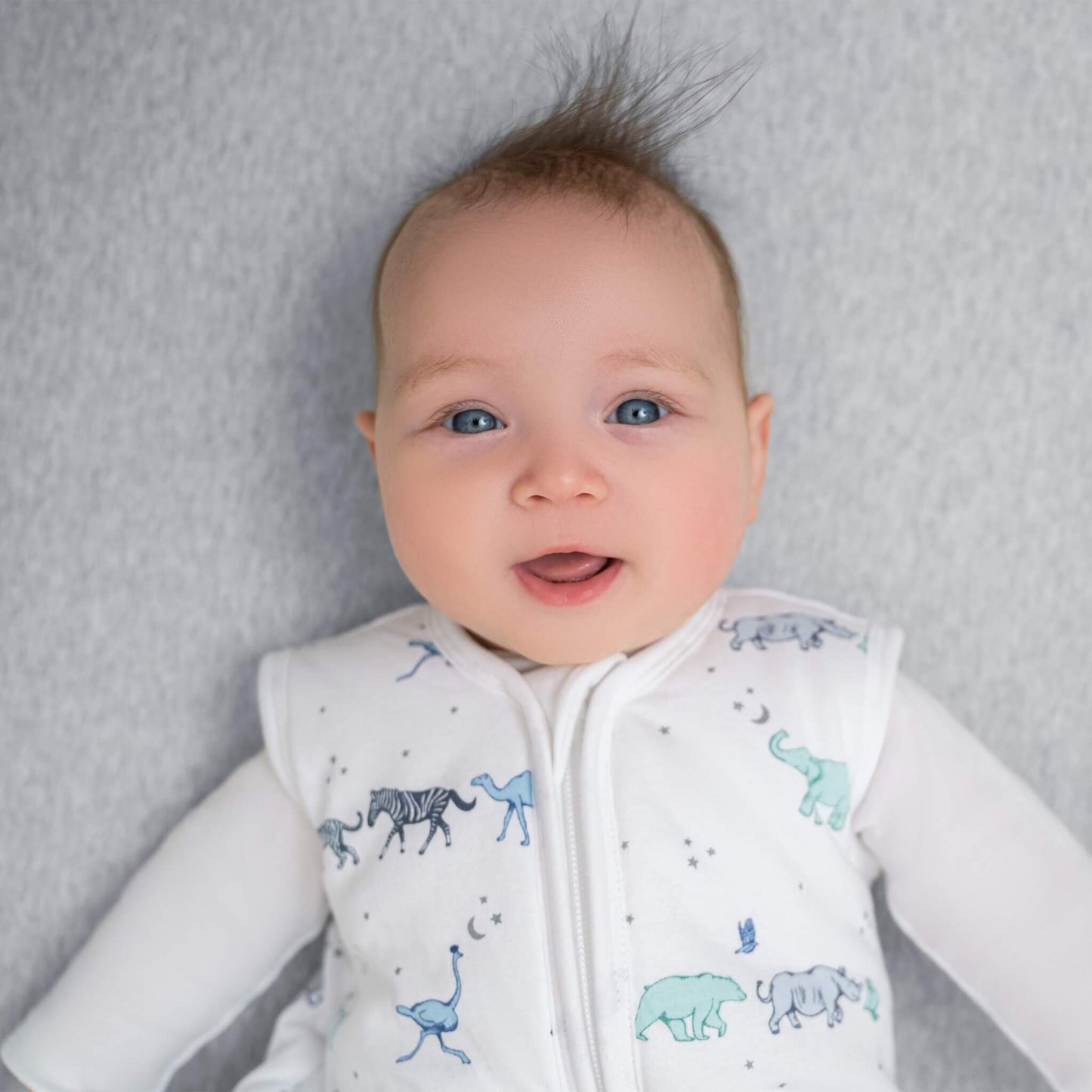 Happy baby wearing aden + anais winter sleeping bag in Rising Star print. Soft, cosy sleepwear with cotton shell for warmth on cold nights.
