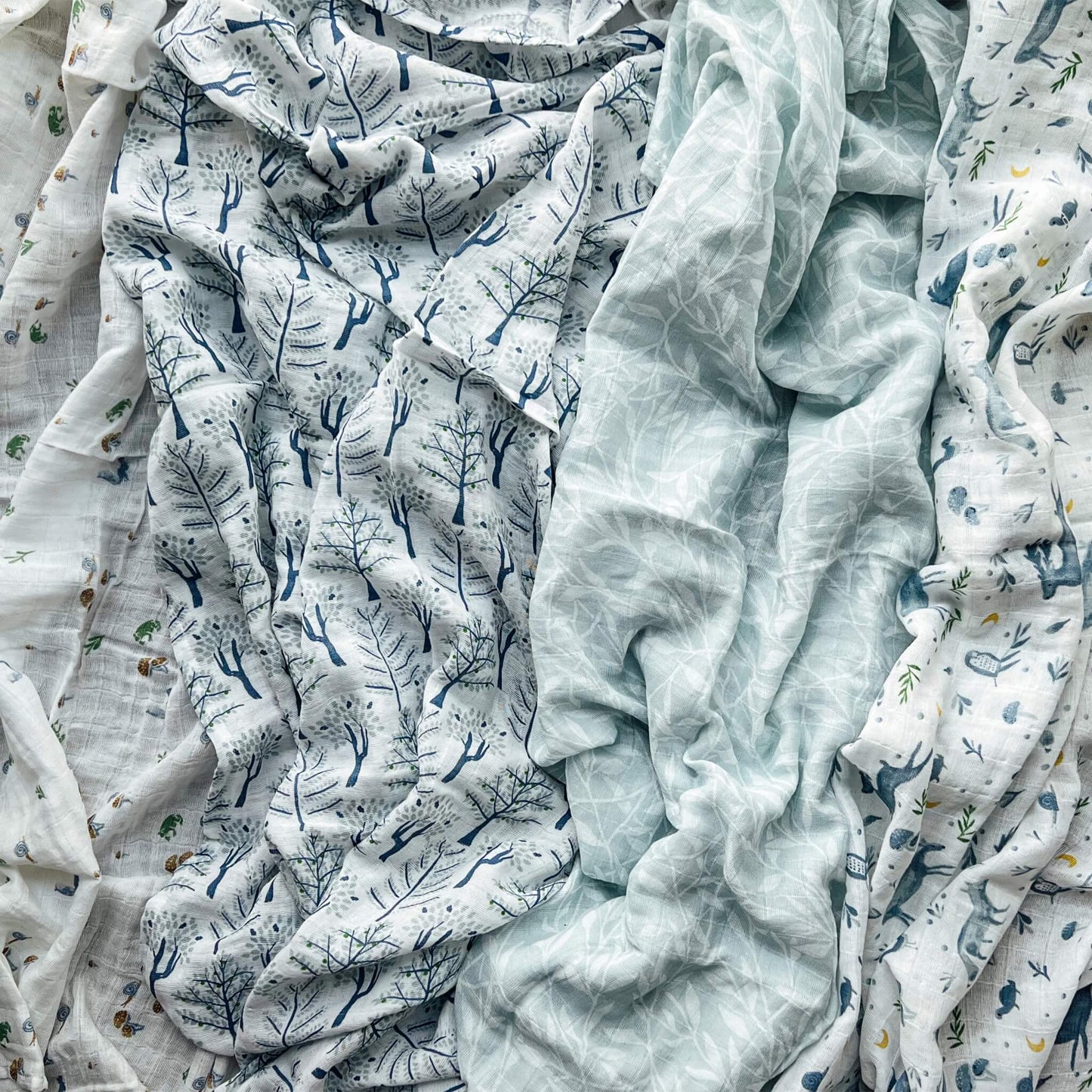 aden + anais Outdoors muslin swaddle set laid out flat showing nature-inspired prints in soft blue and green tones.