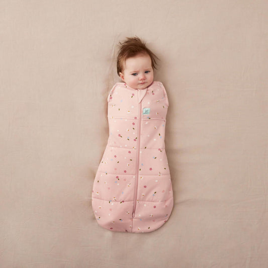 Baby wrapped snugly in a Winter Swaddle Bag (2.5 Tog) with pink floral print, zip-up front, and bell-shaped bottom.