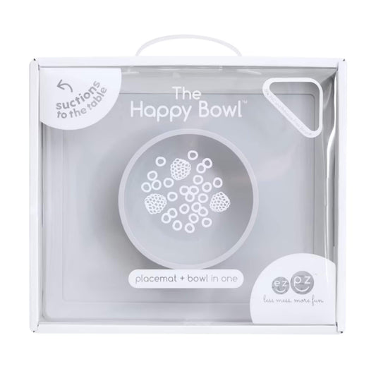 Retail packaging box showing the Happy Bowl in pewter. The front displays a product illustration, the name “The Happy Bowl” and the description placemat + bowl in one.