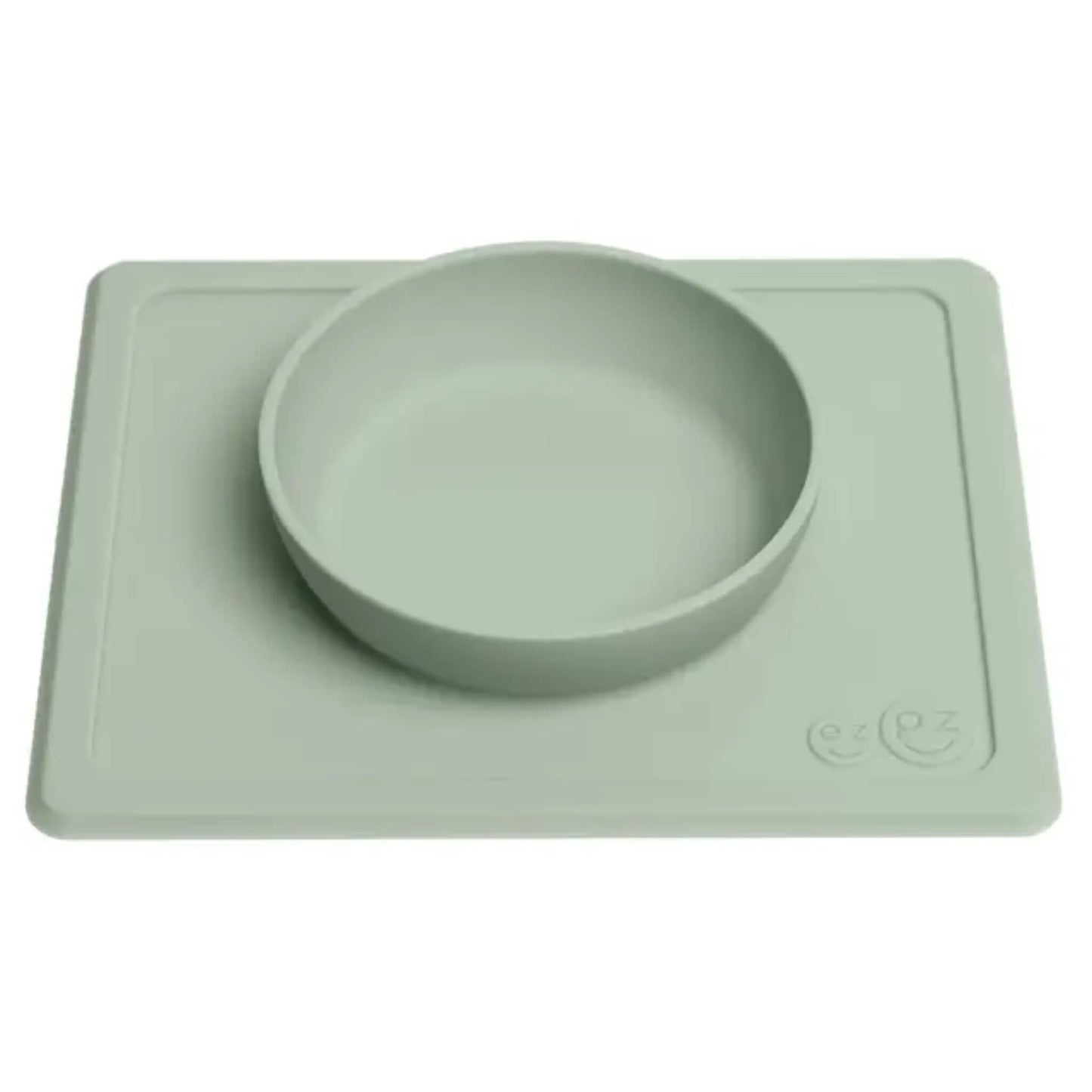 Shallow silicone feeding bowl attached to a rectangular suction placemat in soft sage green.