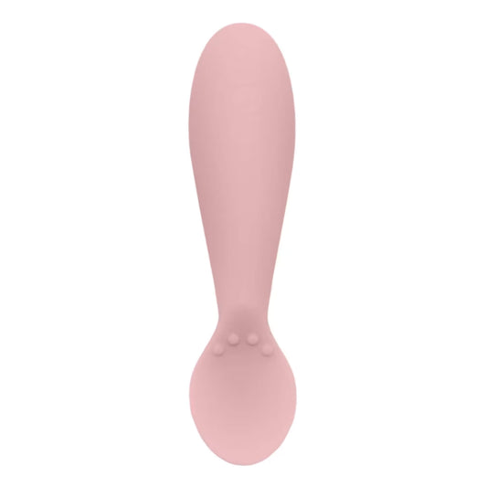 Single blush pink silicone infant training spoon with shallow head and small textured bumps on the handle.