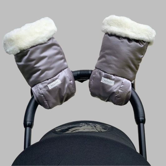 Pair of grey pram gloves with cream fleece lining fitted to a pushchair handle.