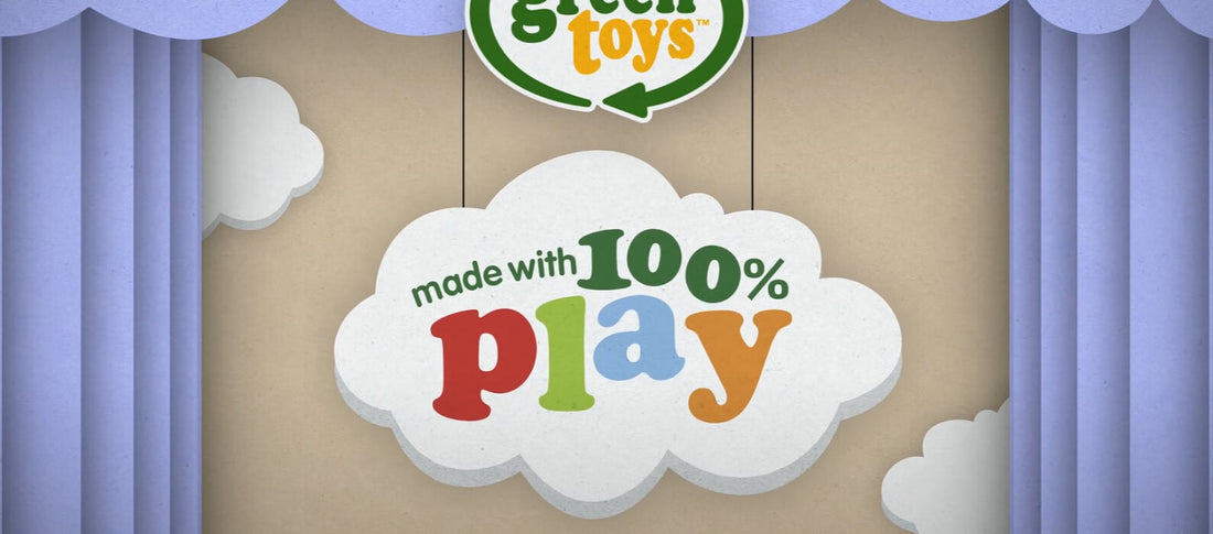 Cloud-shaped sign showing the words made with 100% play against a stage-style backdrop with blue curtains.