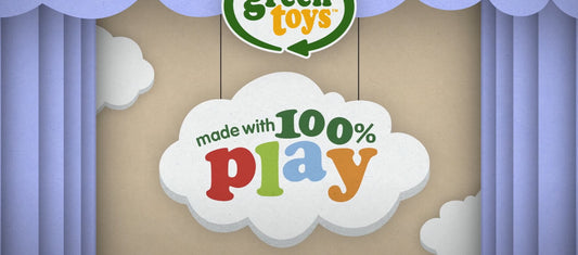 Cloud-shaped sign showing the words made with 100% play against a stage-style backdrop with blue curtains.