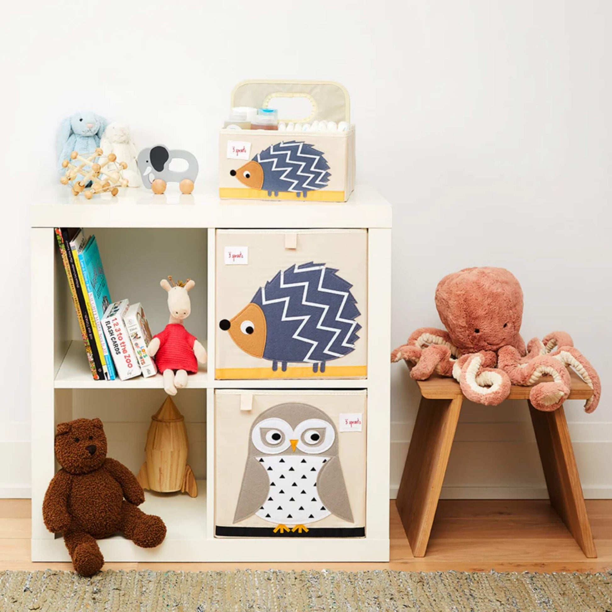 Hedgehog storage box styled in a nursery room setup, placed in a shelving unit next to an owl design box, with soft toys and books around.