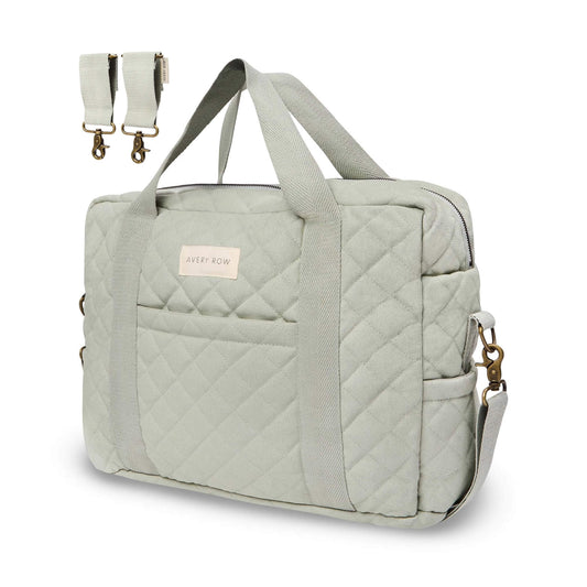 Avery Row baby changing bag in sage green quilted cotton with long shoulder handles, zip top and detachable pram clips shown beside bag.