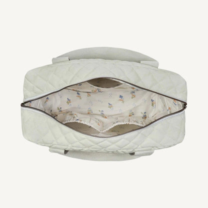 Top view of an open quilted sage green baby changing bag showing spacious interior with patterned lining and elasticated organiser pockets.