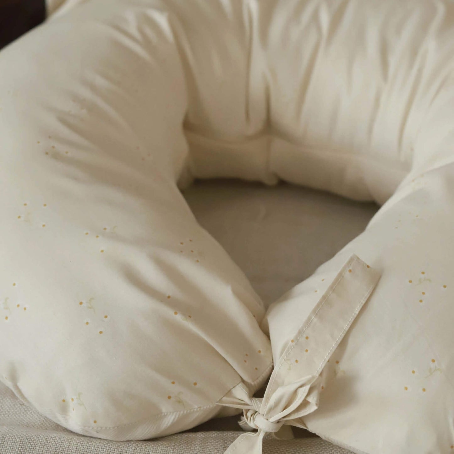 Close-up of a cream nursing pillow showing the Wild Chamomile print and fabric tie fastening.