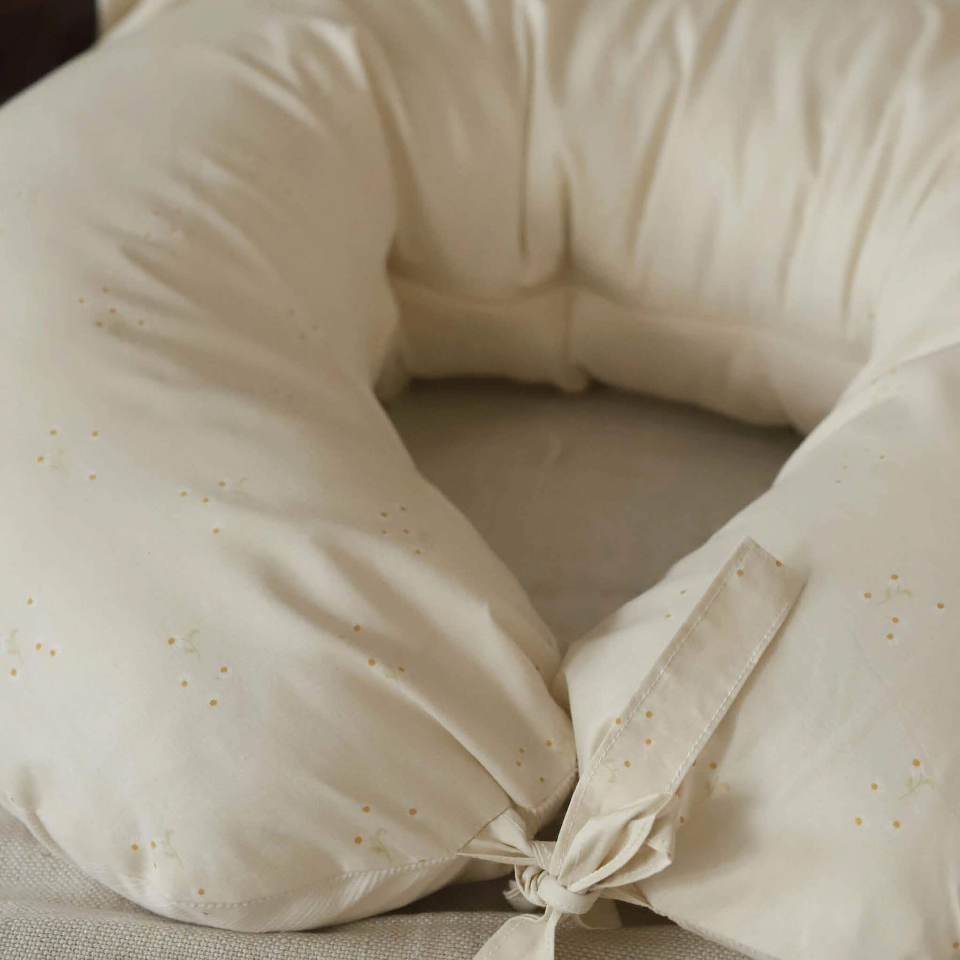 Close-up of a cream nursing pillow showing the Wild Chamomile print and fabric tie fastening.