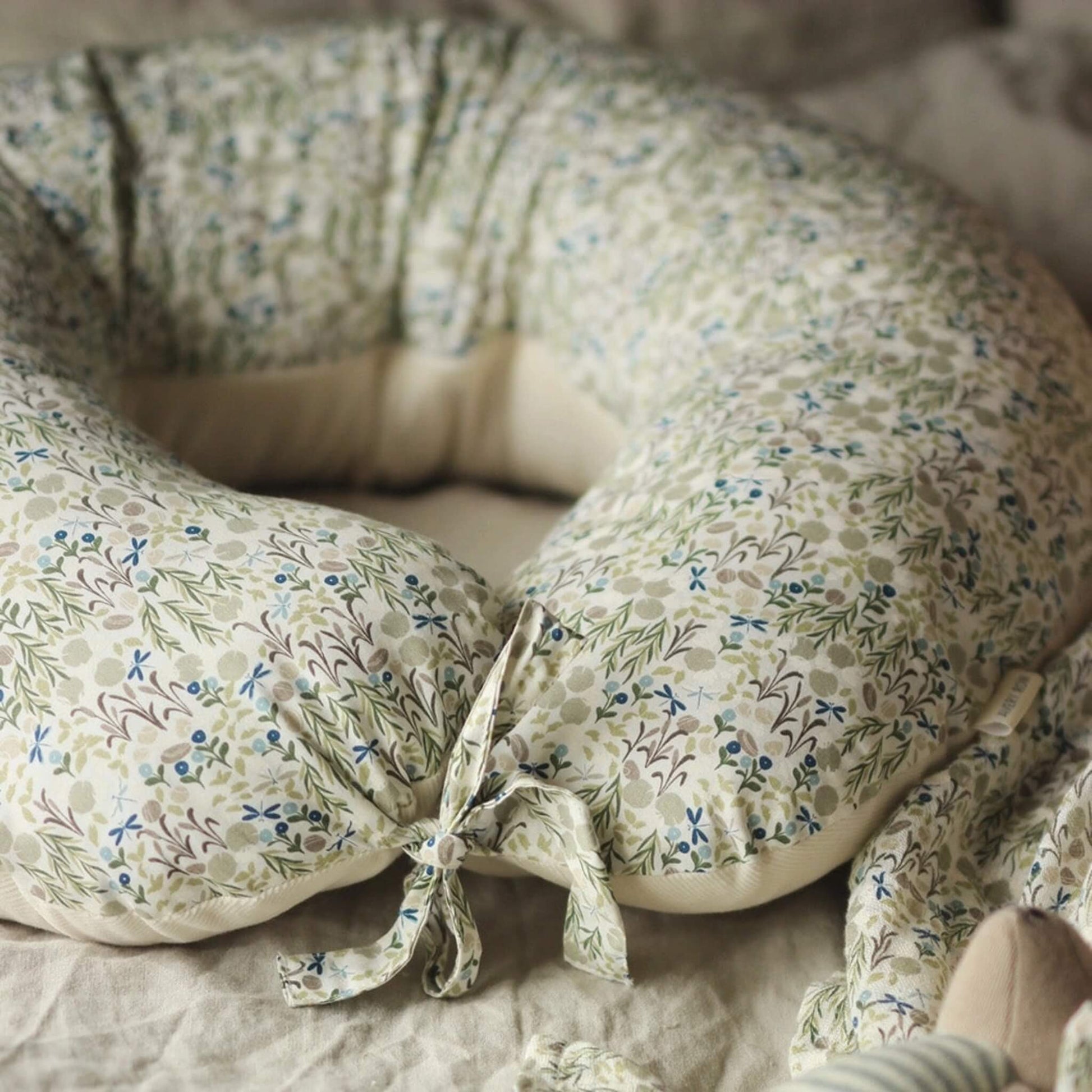 A floral nursing pillow with soft padded sides and fabric tie fastening.
