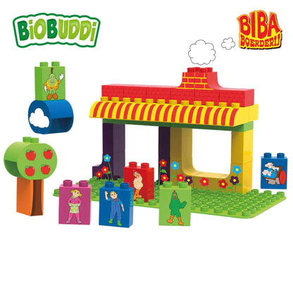 A layout of bright building blocks arranged into a simple farm structure, with character tiles, a tree piece and illustrated background elements.