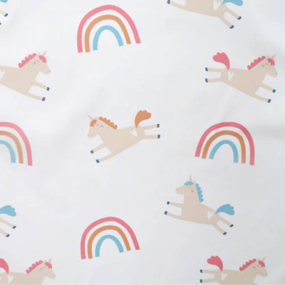 A close-up of a white fabric printed with pastel unicorns and colourful rainbows in pink, orange and blue tones on a soft weaning bib.