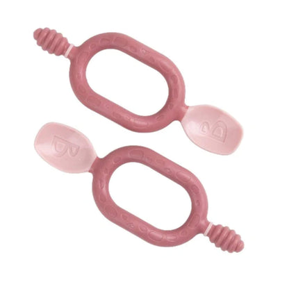 A pair of Bibado Dippit baby spoons in blush pink, showing both dipper and spoon ends with textured oval handles.