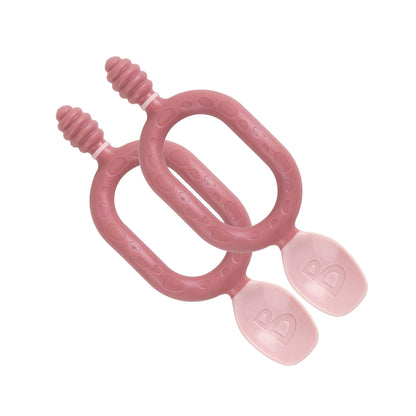 Two blush pink Bibado Dippit baby spoons with looped handles and dual-ended design, shown against a white background.