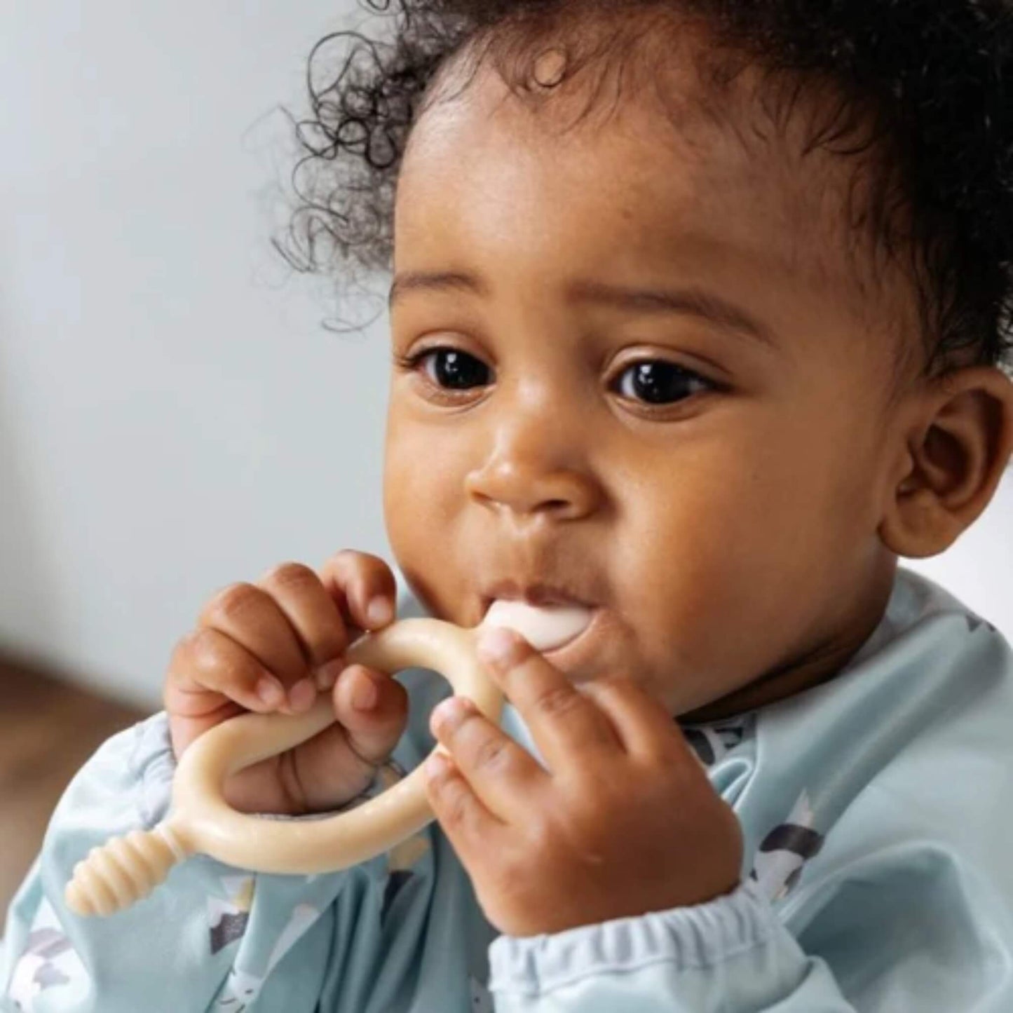 Close-up of toddler carefully mouthing the spoon end of the fawn Bibado Dippit, showing a focused expression.