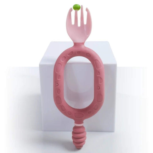 A pair of blush pink self-feeding utensils with dual handles, featuring a textured dipper and spork for babies learning to feed themselves.