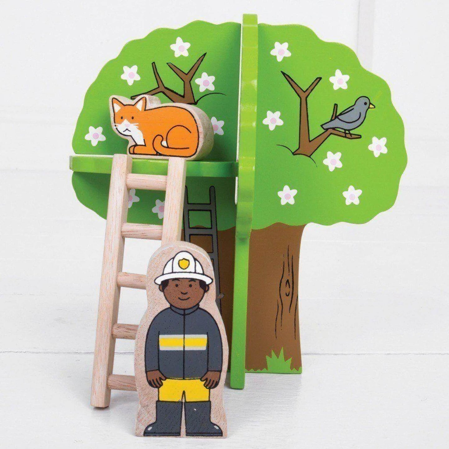 Wooden firefighter figure stands next to a ladder propped against a leafy green tree with a painted bird and a removable wooden cat figure perched on top.