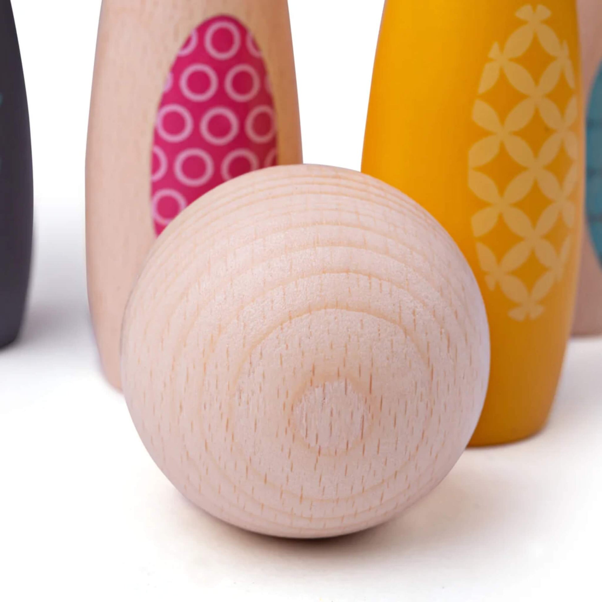 Tightly cropped view of the wooden bowling ball with skittles visible behind.