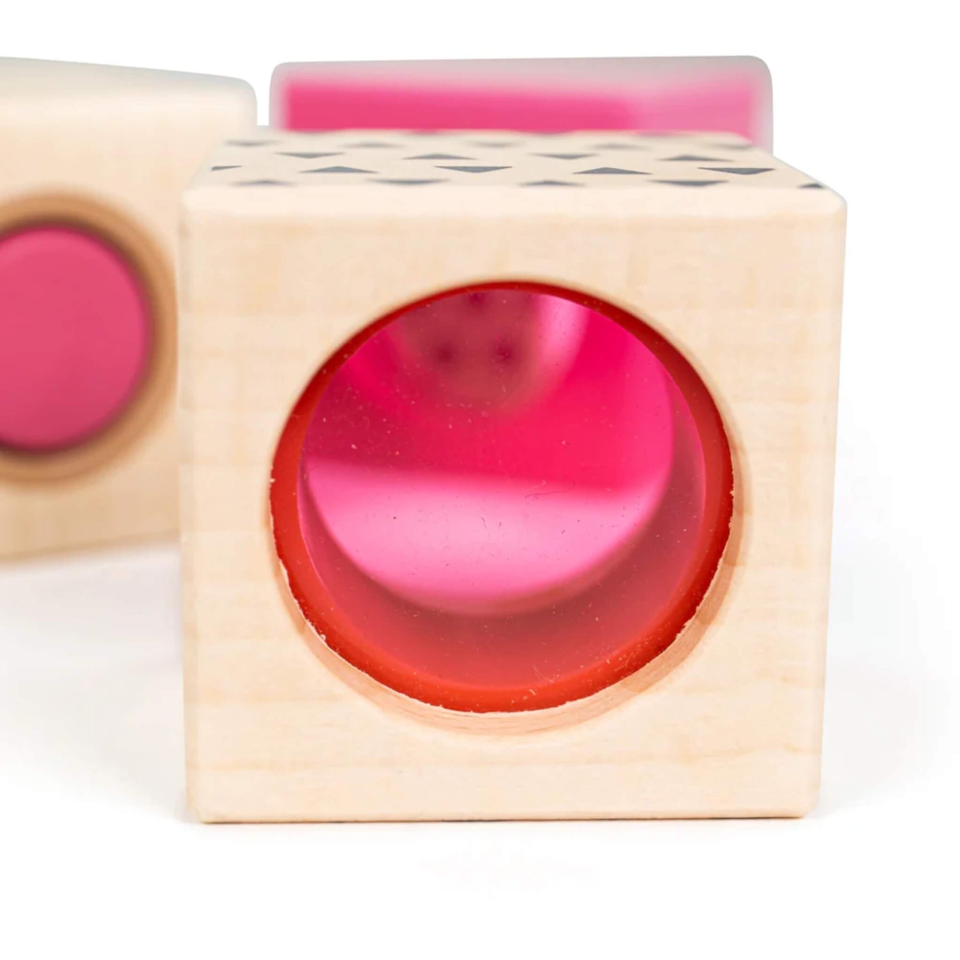 Zoomed-in view of the pink viewfinder block, showing its tinted acrylic lens and soft natural wood frame.