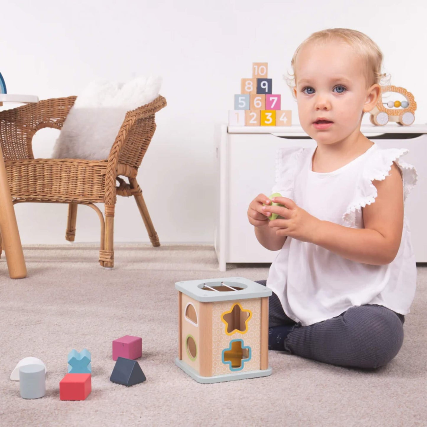 Toddler holding a green shape with the Bigjigs Shape Sorter and five pieces arranged in front.