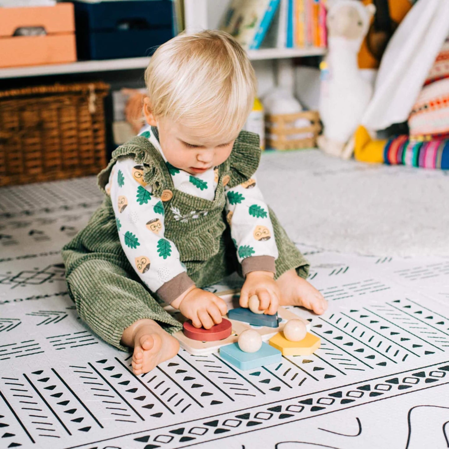 Toddler playing with the Bigjigs animal shape puzzle on a patterned playmat in a cosy room.