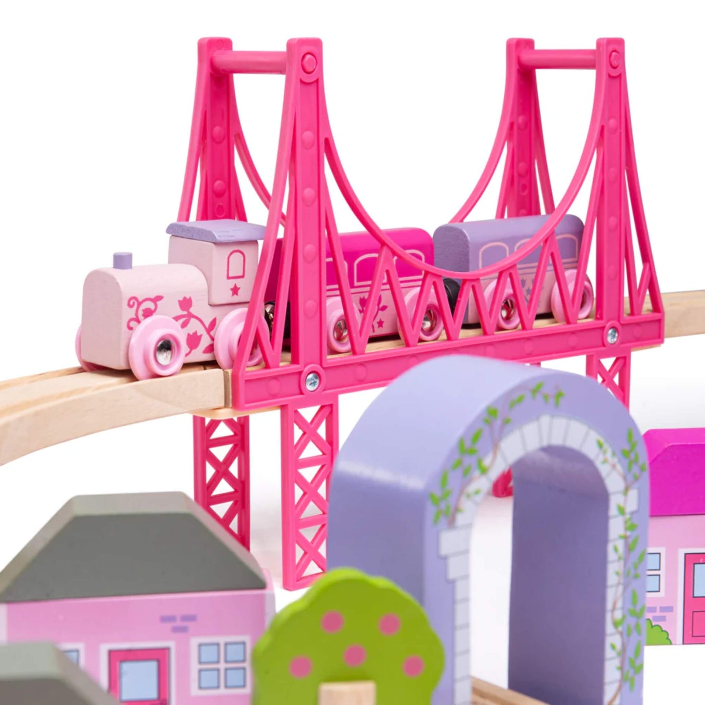 Zoomed-in view of the pink suspension bridge with the pastel pink fairy train crossing, surrounded by colourful wooden buildings and trees.