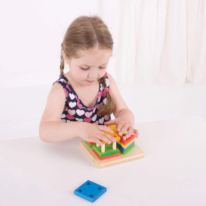 Young child concentrating as they stack and sort the brightly coloured wooden pieces on the pegged baseboard – building fine motor skills.