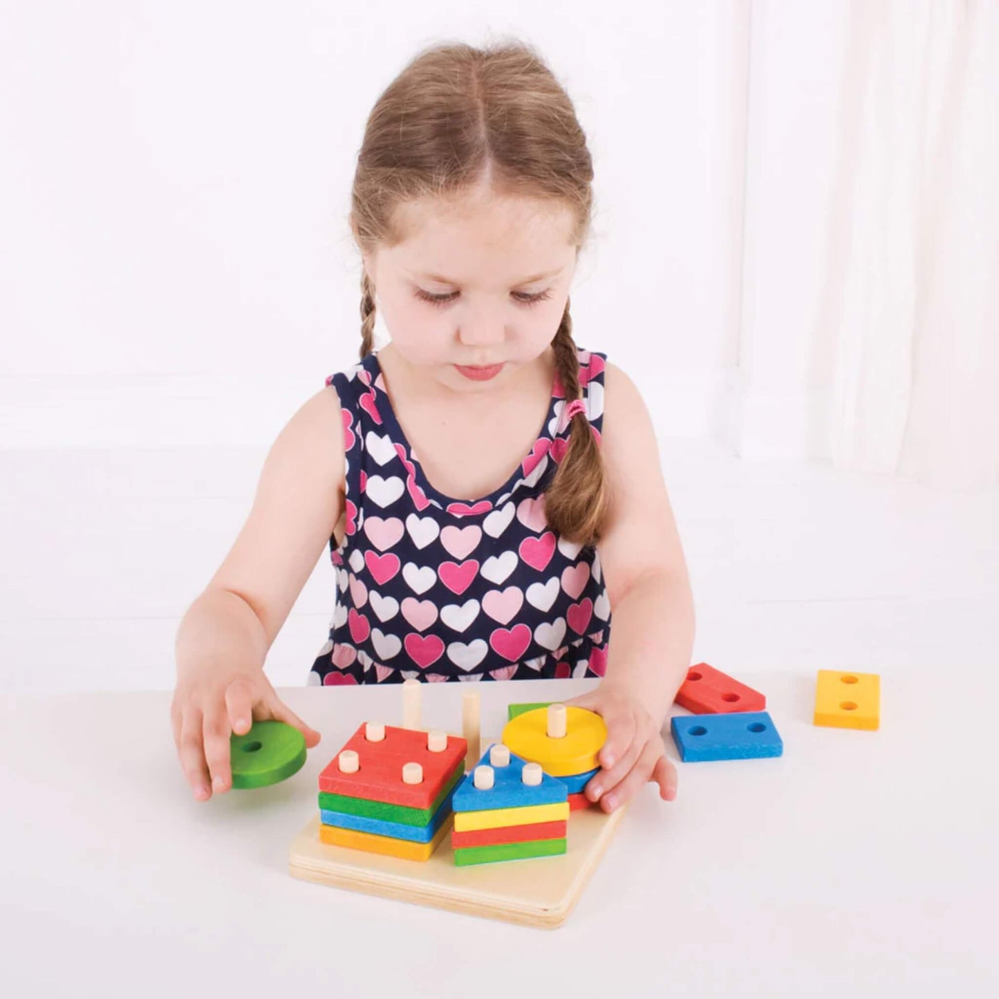 Child carefully placing a round wooden piece onto the pegged baseboard, encouraging hand-eye coordination and problem-solving.