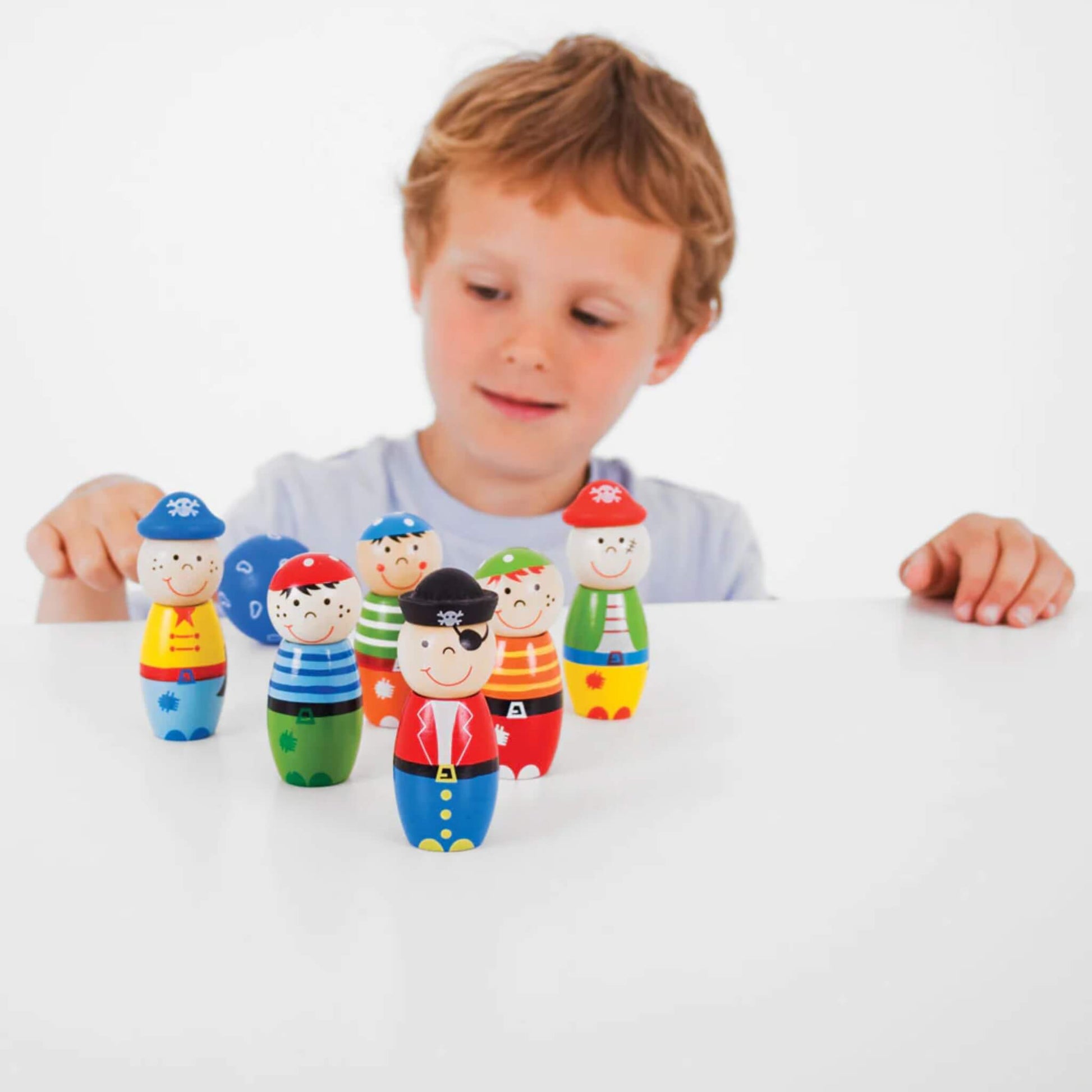 Child getting ready to roll the ball towards the upright skittles, set against a white background.