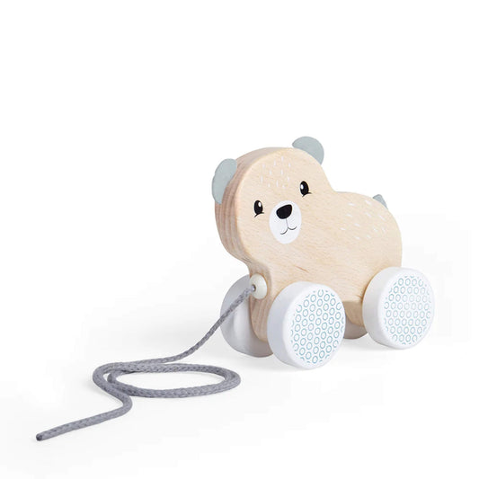 Side view of the pull along bear toy showing its light wooden body, grey ears and tail, and blue patterned wheels.