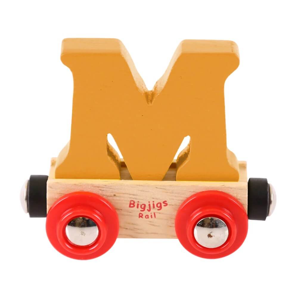 A wooden toy train carriage with a bright orange letter 'M' on top and red wheels, labeled 'Bigjigs Rail'.