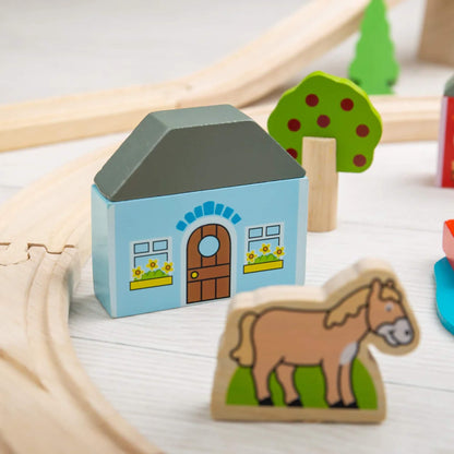 Wooden horse figure and light blue house with flower boxes from the Bigjigs Toys Town & Country Train Set, positioned near curved track pieces.