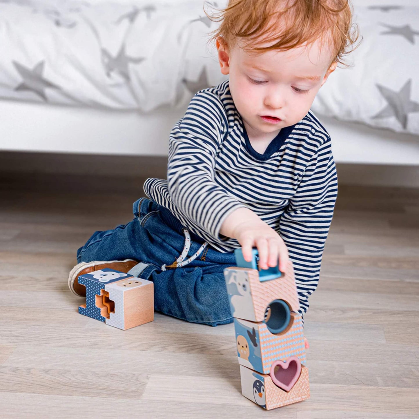 Close-up of toddler balancing wooden Arctic tower pieces, promoting dexterity and problem-solving.