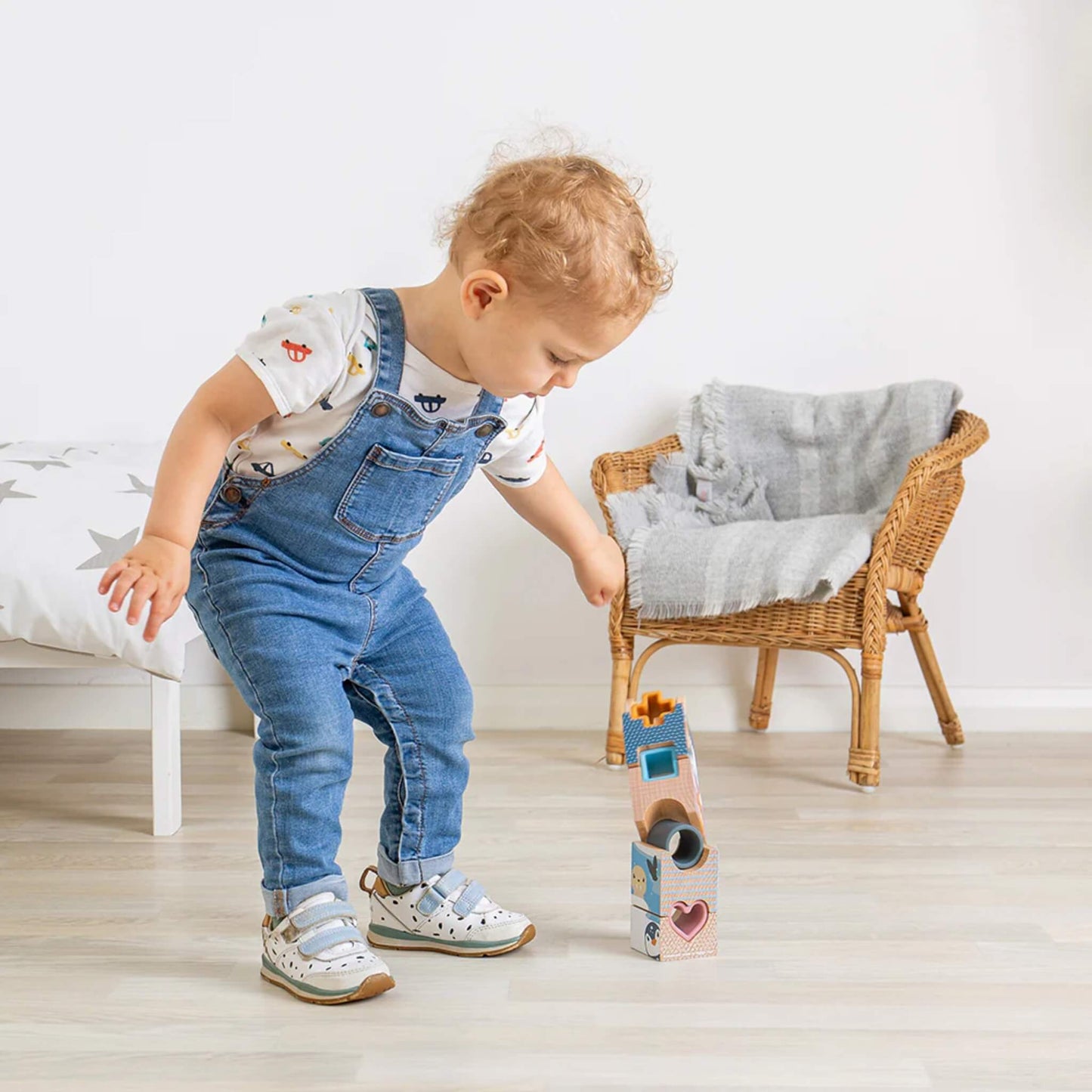Toddler arranging Arctic-themed stacking blocks on a wooden floor, exploring shapes and balance.