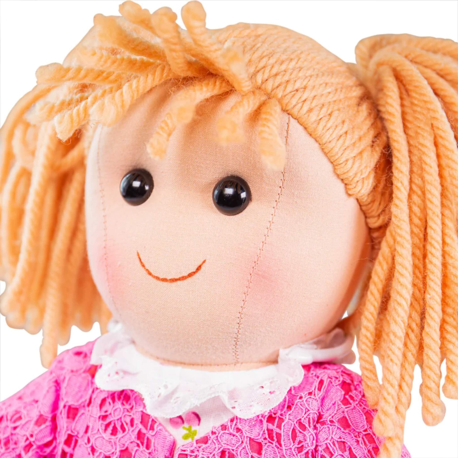 Close-up of the doll’s smiling face, with black stitched eyes and curly blonde yarn hair tied in bunches.