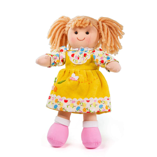 Bigjigs Toys Daisy Doll (Small) standing upright in a yellow cord dress with floral trim, pink shoes and soft yarn pigtails.