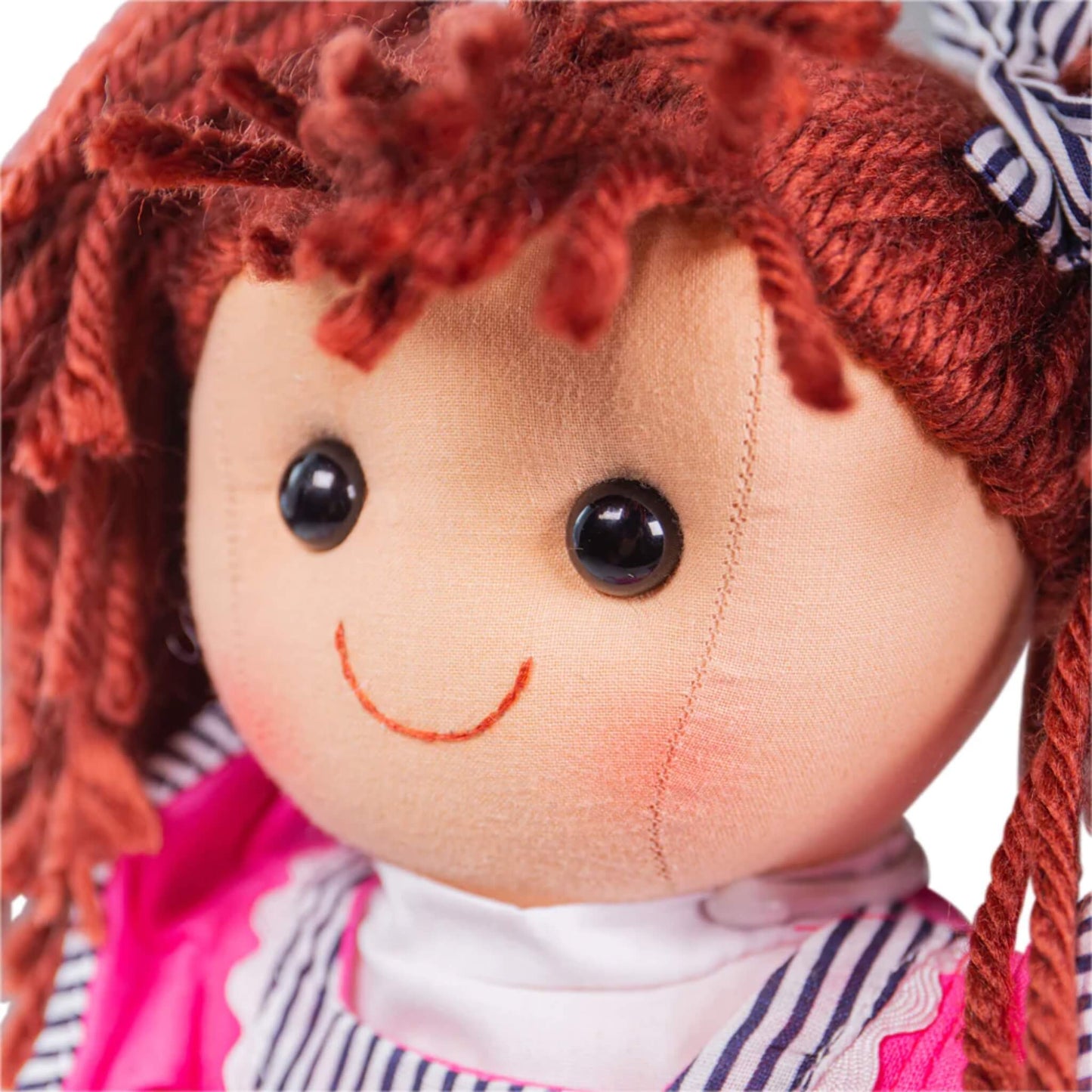 Angled close-up of Emma's stitched face, with rosy cheeks and embroidered smile.