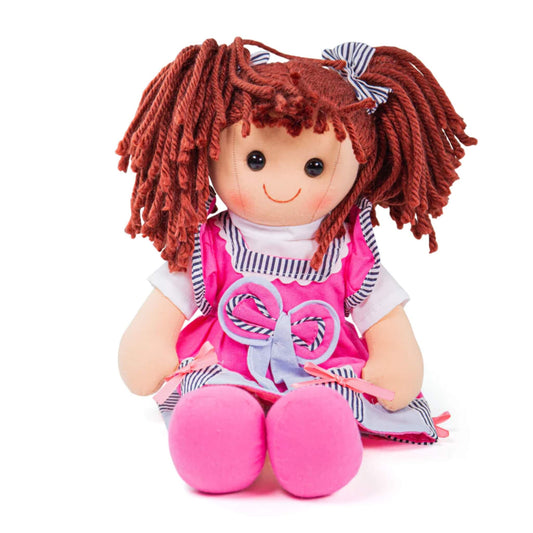 Soft ragdoll Emma sitting upright with bunches tied in striped bows and bright pink shoes visible.