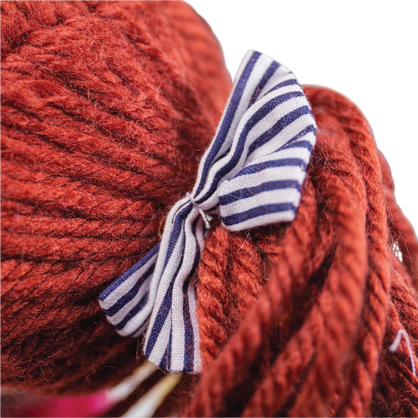 Close-up of Emma's brown yarn hair tied with a navy and white striped bow.