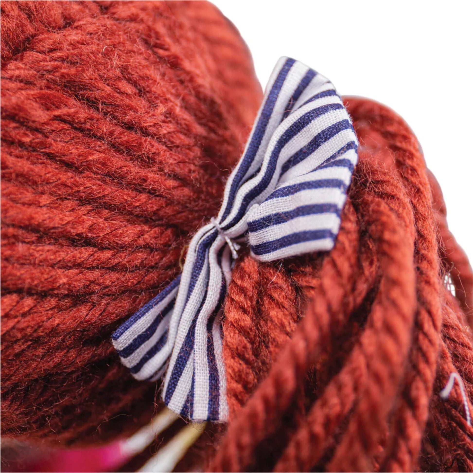 Close-up of Emma's brown yarn hair tied with a navy and white striped bow.