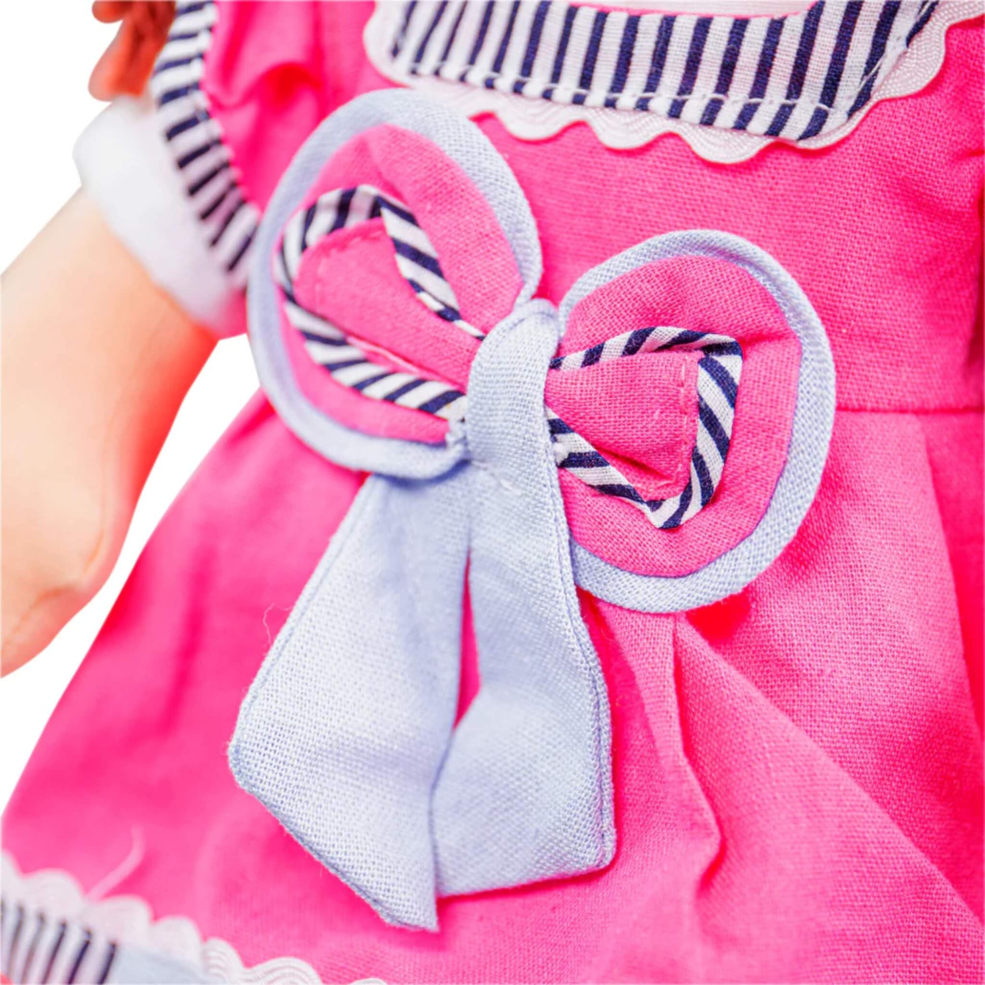 Embroidered bow detail on Emma's dress with contrast blue tails and striped edging.