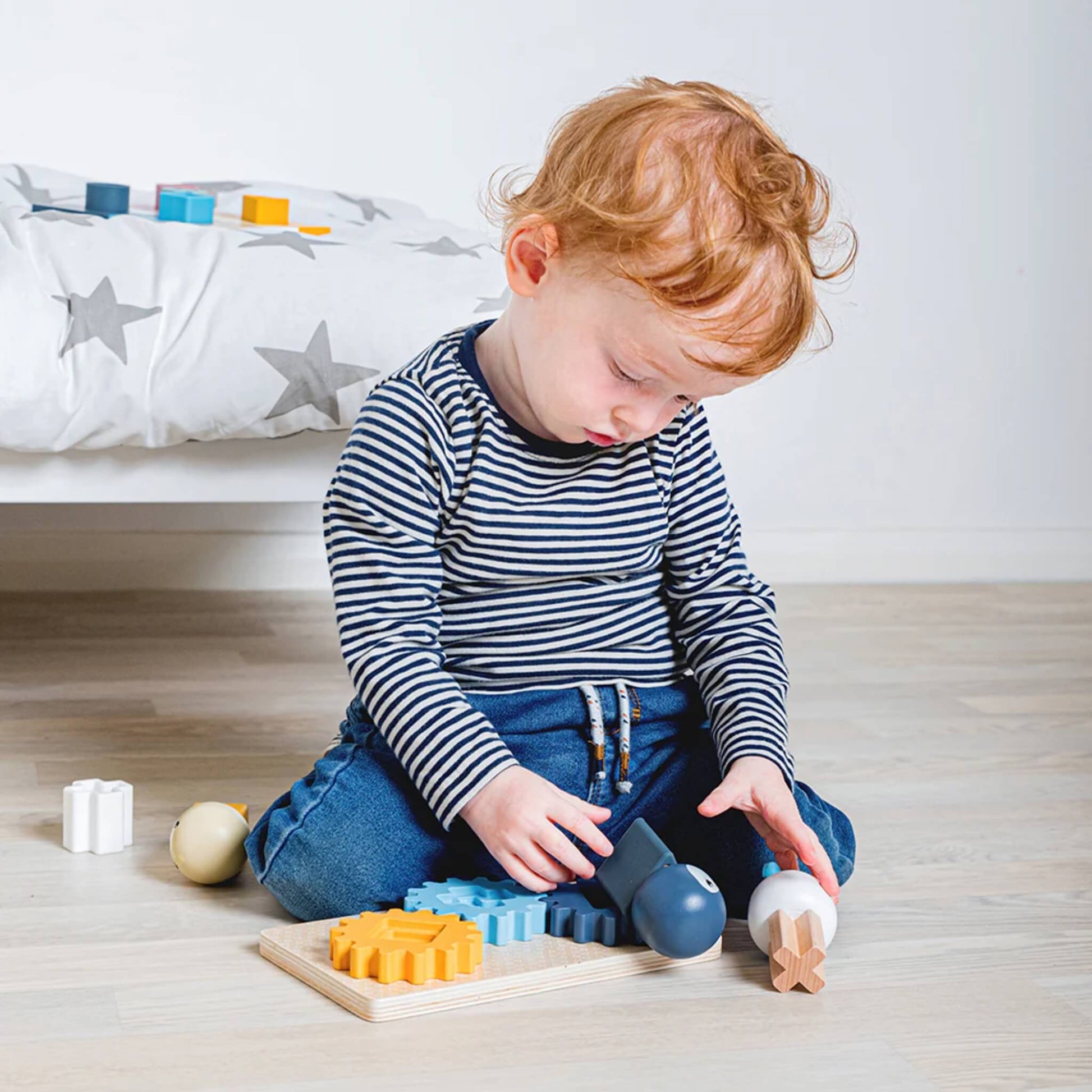Child playing with the Arctic Cog Board, stacking and spinning pieces while exploring shapes and colours.