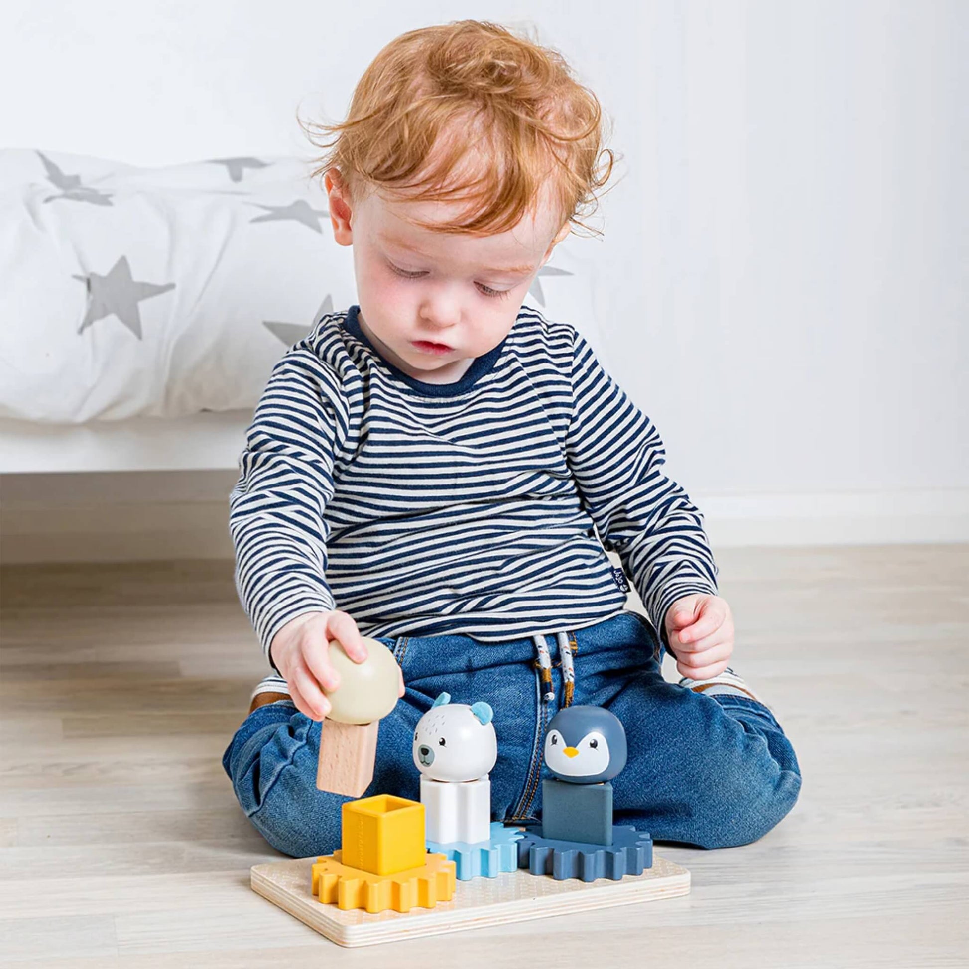 Child engaged with the Arctic Cog Board, rotating cogs and sorting pieces for hands-on learning.