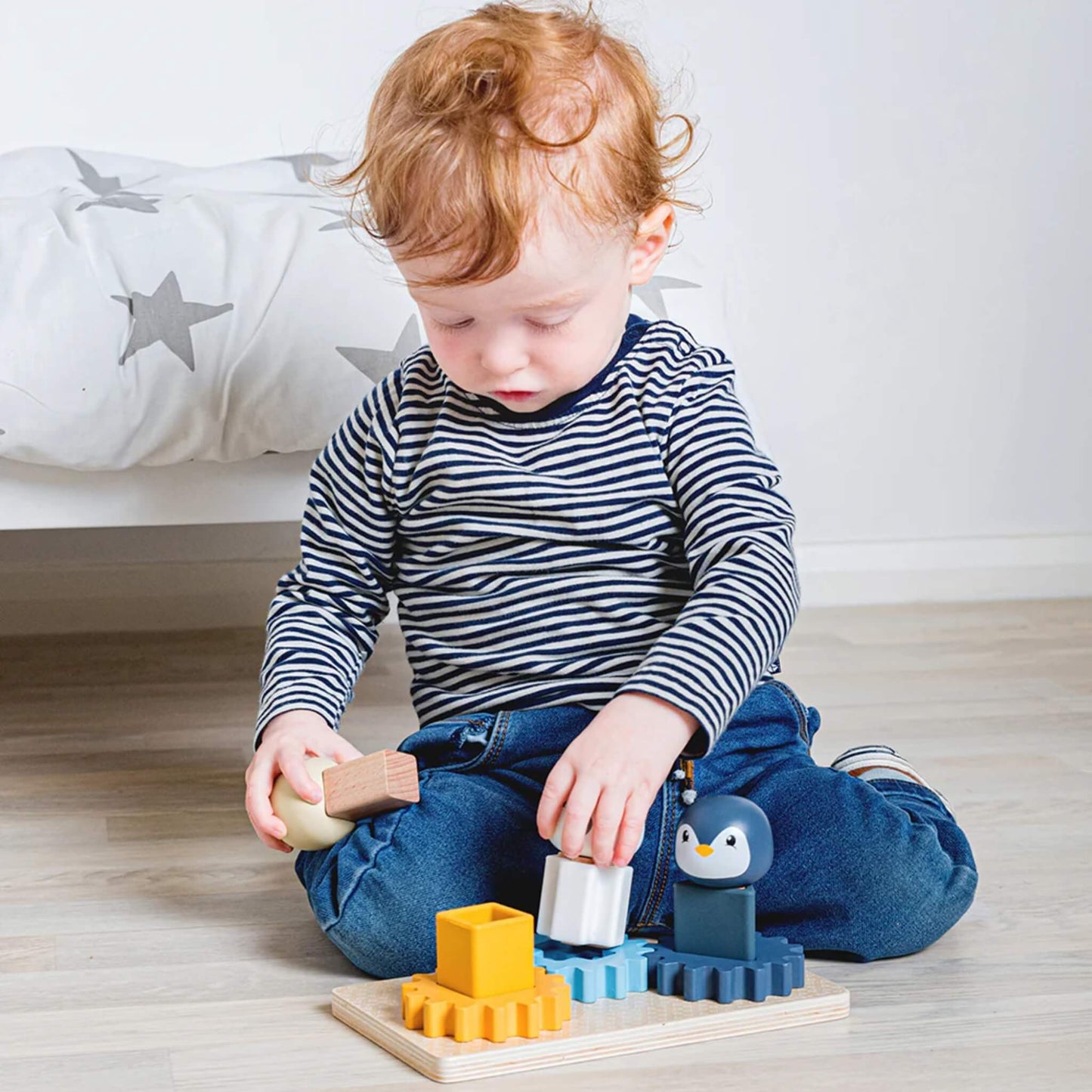 Toddler stacking the walrus figure onto the yellow cog, developing fine motor skills and spatial awareness.