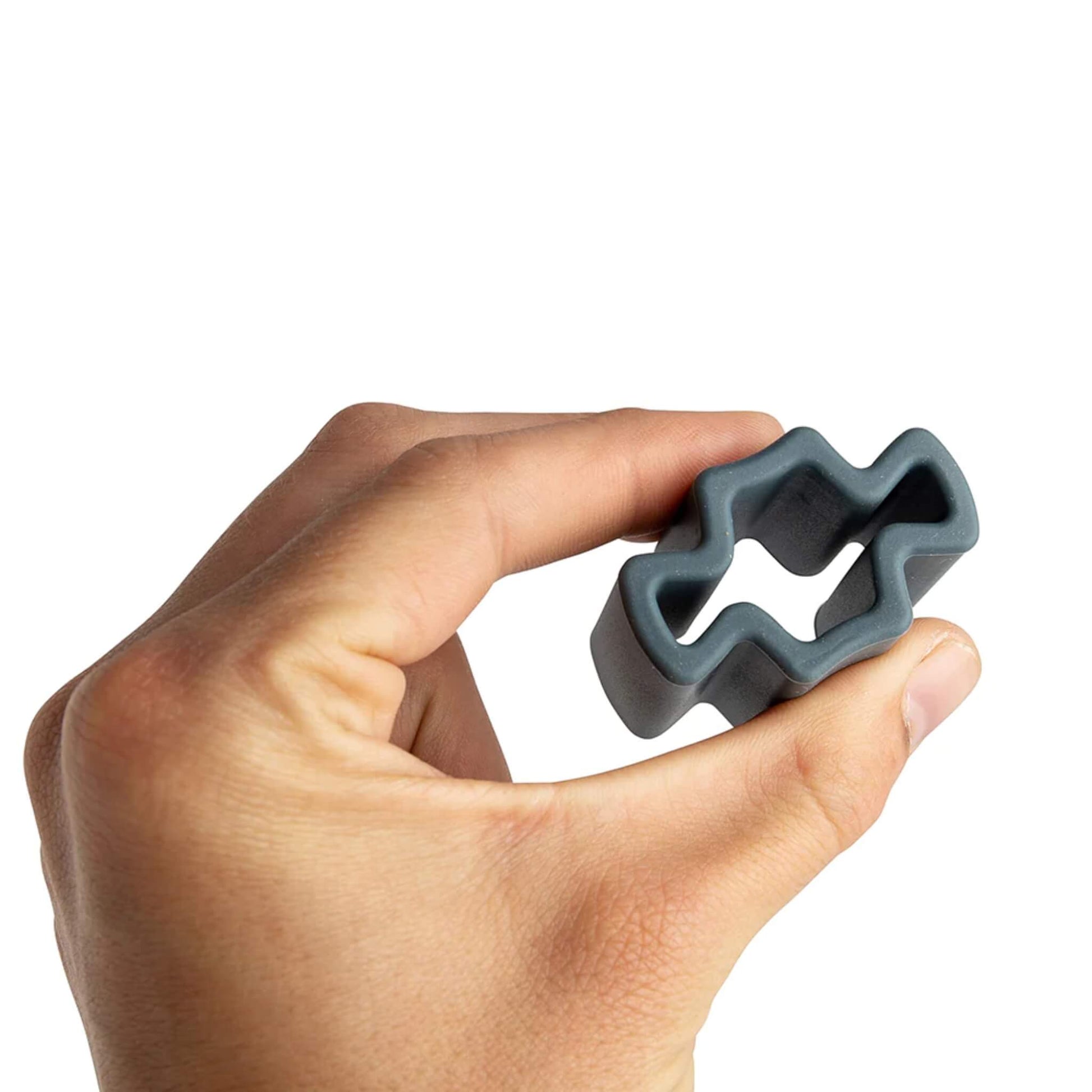 A close-up of a hand holding a grey silicone cross piece, showing its size, shape, and soft flexible material.